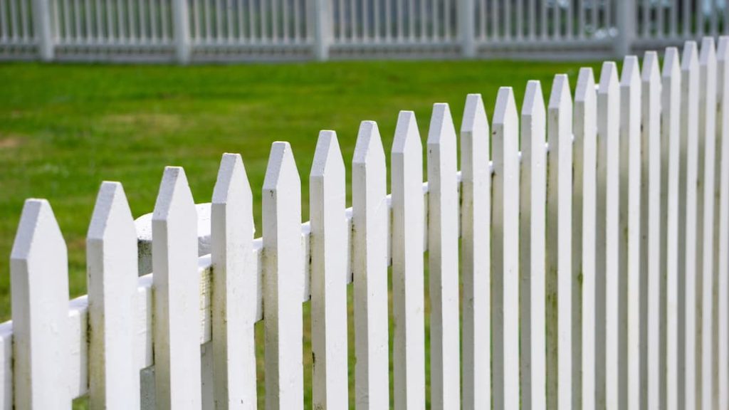a white picket fence with grass in the background